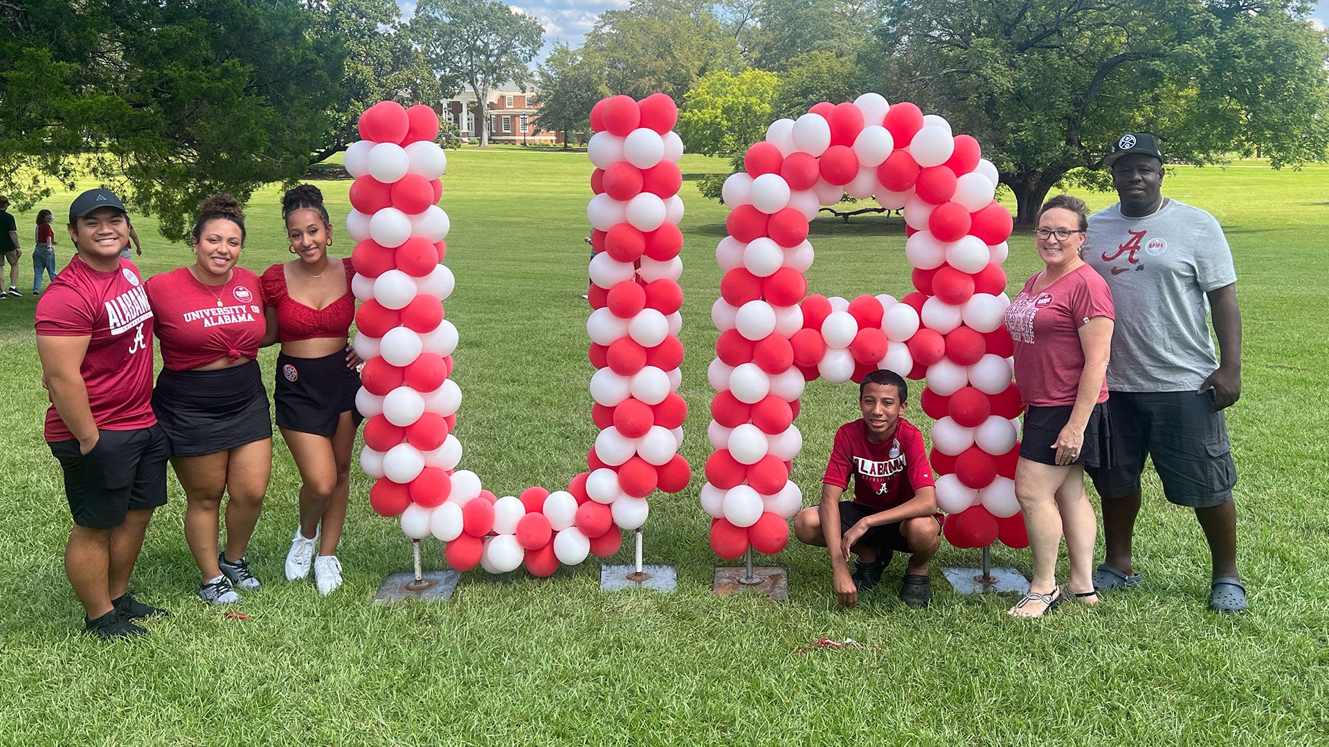 Ciara and her family posing with balloon art spelling "UA"