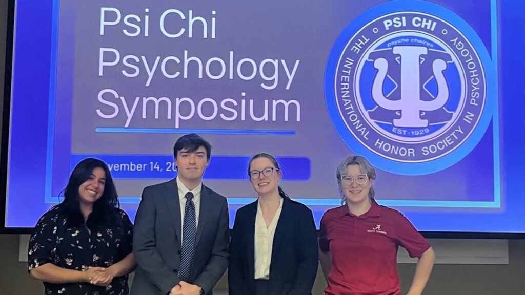 Price posing with peers at Psi Chi Psychology Symposium
