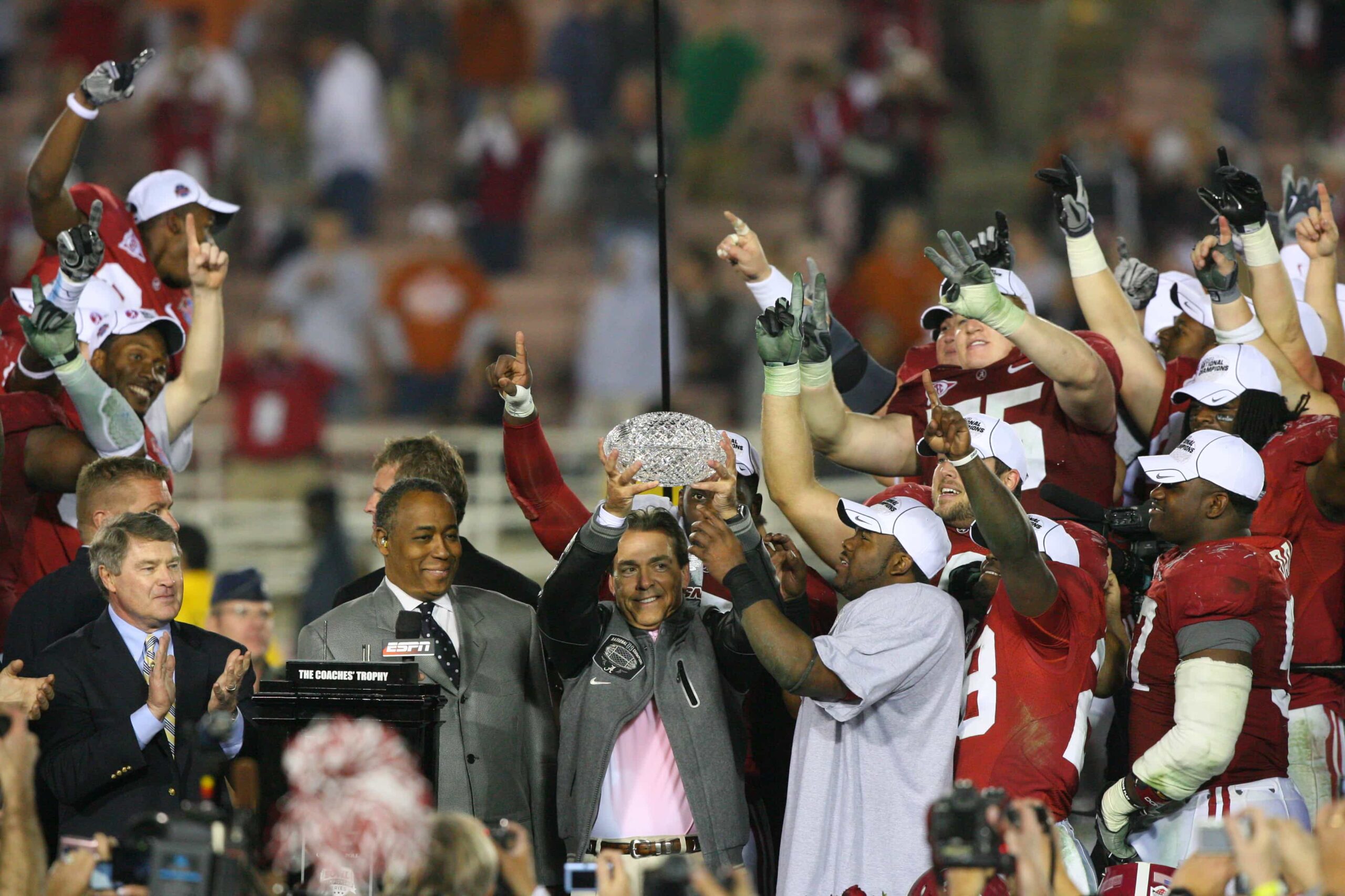 Nick Saban holds up the Coaches’ Trophy as the Crimson Tide celebrate their 2009 BCS National Championship victory over Texas, surrounded by players and staff.