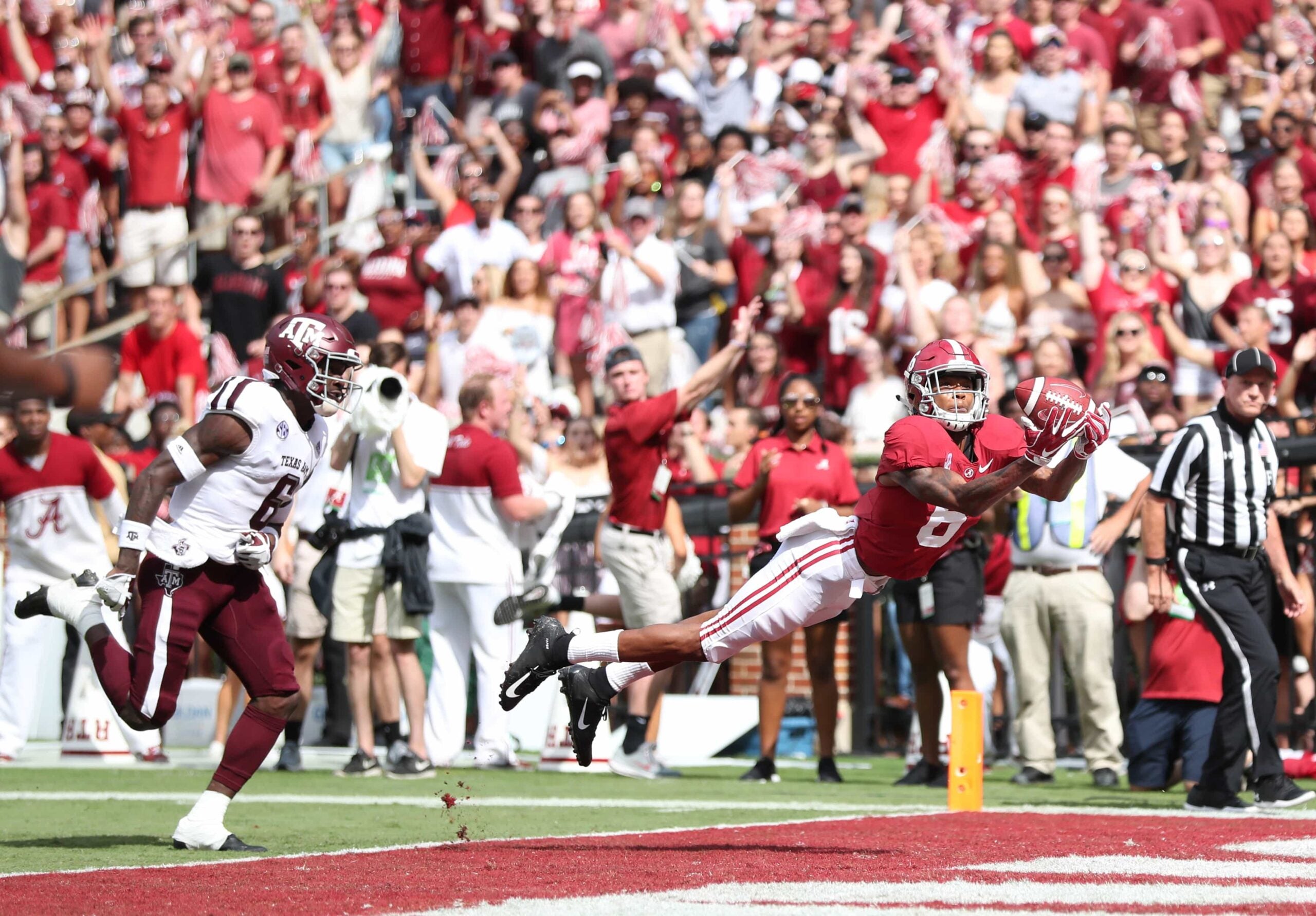 DeVonta Smith dives into the end zone to catch a touchdown pass against Texas A&M, as fans celebrate in the background
