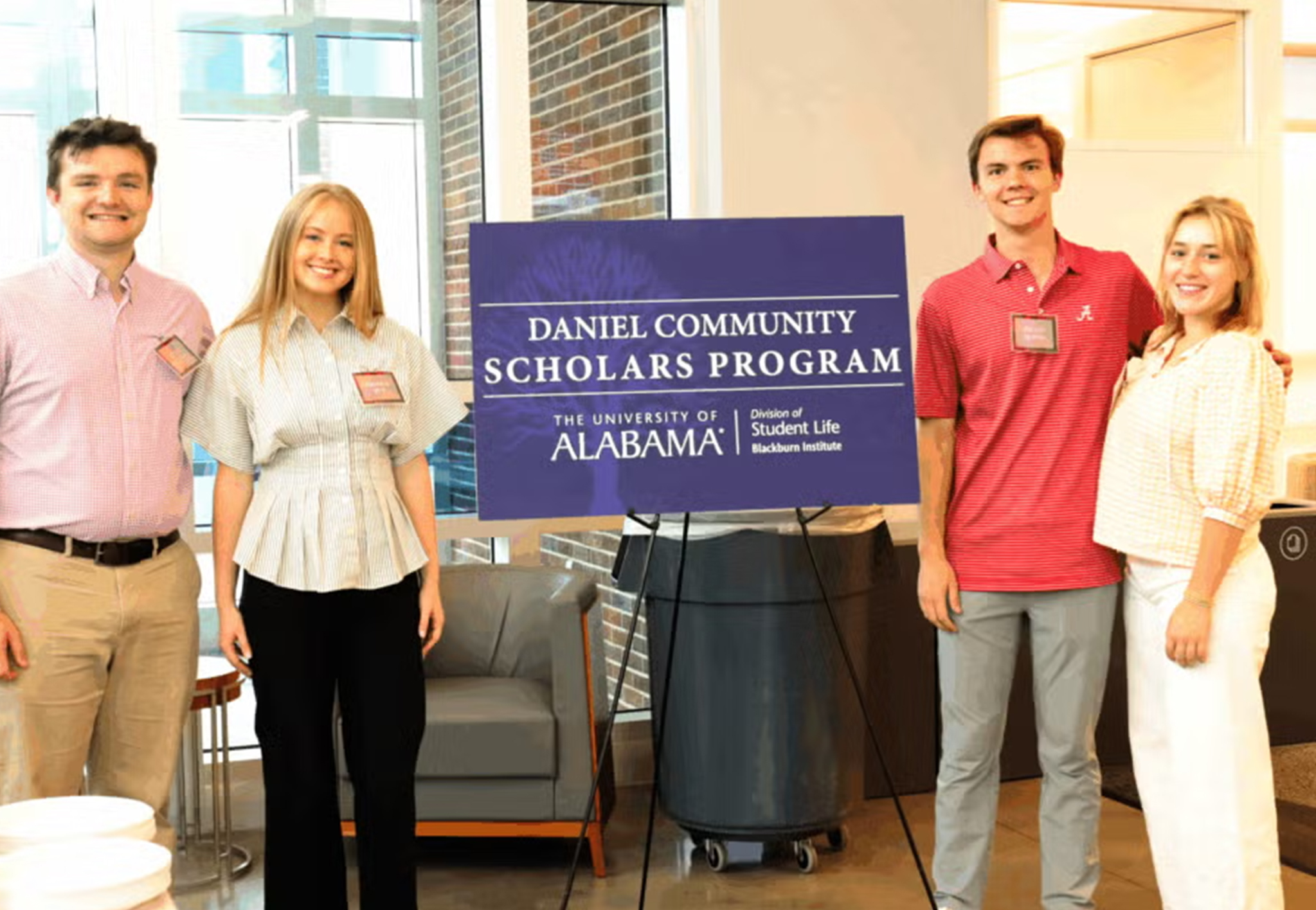 Four students stand on either side of a purple sign reading