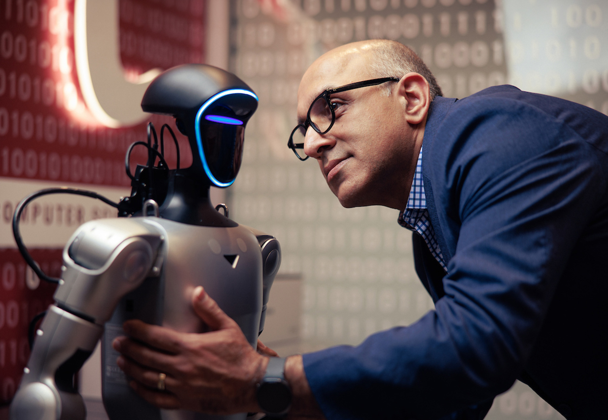 Dr. Rahimi leans in close to a humanoid robot with a glowing blue face ring
